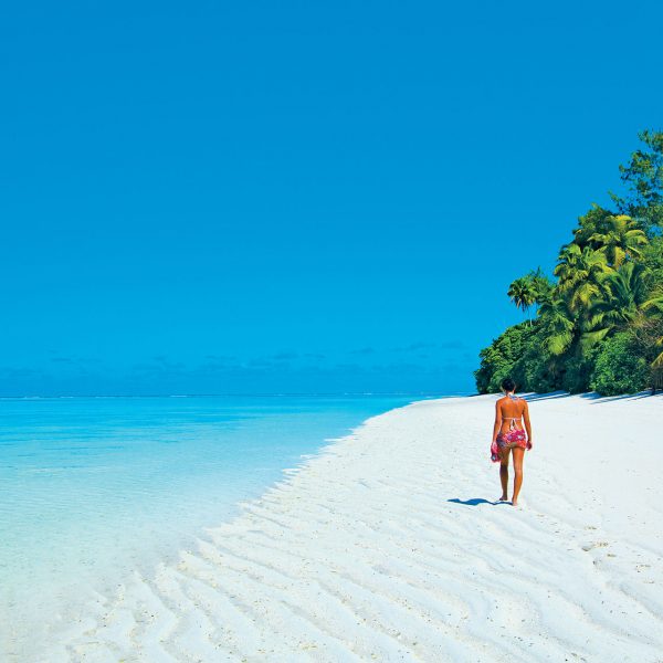 A guest on a walk on the pristine white beach, with no one around her