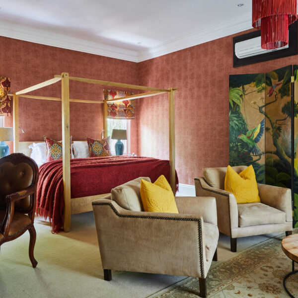 The red bedroom at Domain with a four poster bed, chairs, and beautiful art