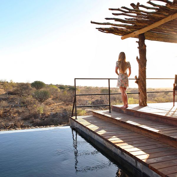 A guests overlooks the water below from the deck around the pool at Mwiba Lodge