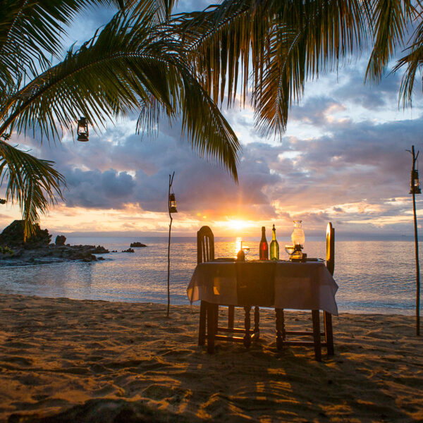 A romantic dinner setup on the water's edge as the sun sets