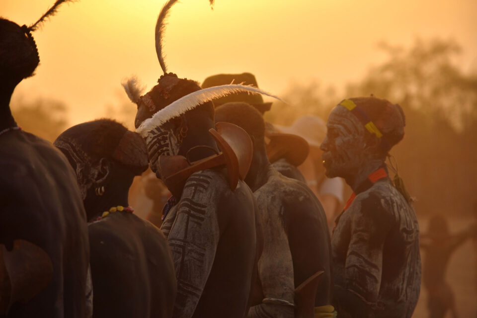 Tribesmen in their traditional attire at sunset with orange hue