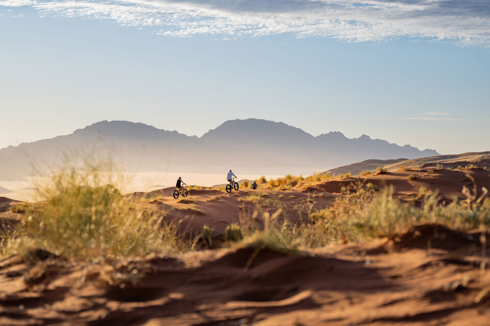 Guests biking through the dunes with mountains in the background